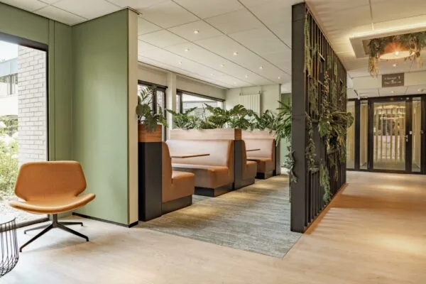 Moderne en groene wachtruimte in het gebouw van Burgemeester Verderlaan met zitbanken, planten en een stijlvolle inrichting.